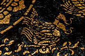 Wat Xieng Thong temple in Luang Prabang, Laos. Detail of the  intricate gold stencilling on black lacquer that decorate the walls of the sim. 